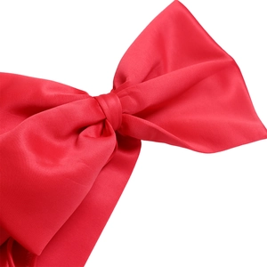 Detail of a large red satin bow with silky gloss and handmade knot on the elegant dress