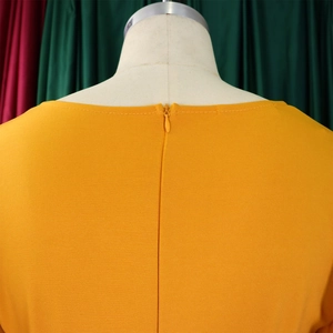 Detail shot of invisible zipper closure on the back of mustard yellow V-neck dress