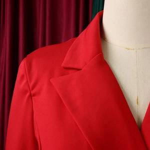 Detail shot of the wide peaked lapels and textured red fabric on a tailored blazer dress