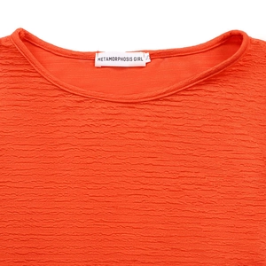 Détail du haut orange montrant la texture gaufrée du tissu et l'étiquette de taille