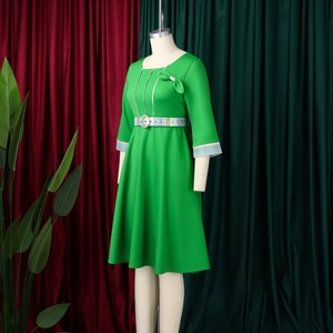 Detail of elegant green midi dress with shoulder bow and plaid belt on mannequin
