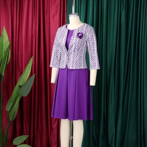 Détail d'un ensemble élégant robe violette et veste imprimée avec broche fleurie
