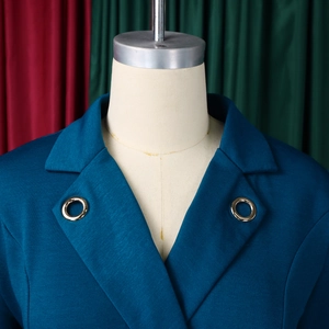 Détail du col d'une robe blazer bleu canard avec des anneaux dorés élégants sur le revers