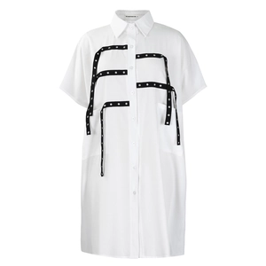 Detail of white cotton shirt dress featuring black decorative ribbons and metal rivets