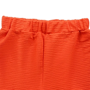 Gros plan d'un short plissé orange vif avec taille élastiquée et texture gaufrée unique