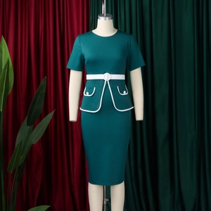 Dettaglio dell'abito verde scuro con cintura bianca e tasche con profili a contrasto