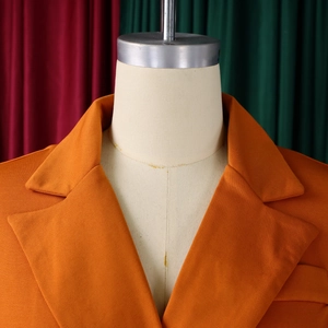Detail of orange double-breasted blazer dress with classic lapel and textured fabric