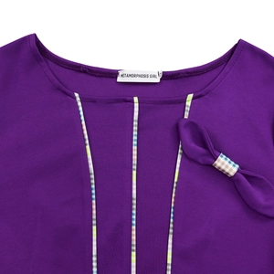Detail of purple round neck dress showing striped trim, bow, and brand label