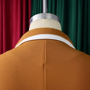 Detail of caramel crepe dress showing white contrast collar piping and fabric texture