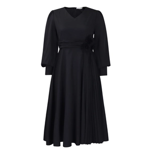 Detail of elegant black V-neck maxi dress featuring waist flower and pleated skirt
