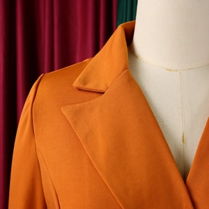 Close-up of orange long sleeve dress featuring classic notch lapel and twill fabric