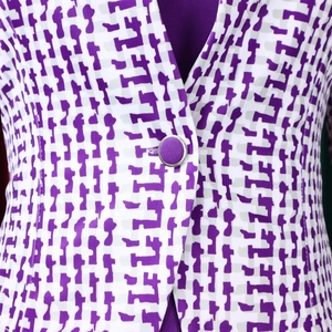 Détail de l'ensemble géométrique violet et blanc avec un bouton en tissu bordé d'argent