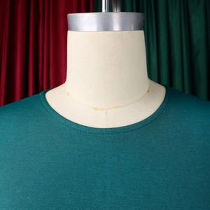 Dettaglio di un abito verde scuro con scollo rotondo e trama in maglia orizzontale fine