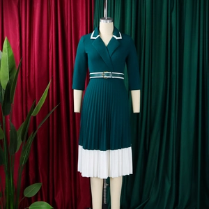 Detail of dark green pleated A-line dress with white contrast trim and waist belt