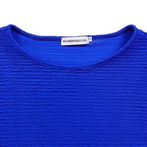 Vue détaillée du tissu gaufré bleu roi avec étiquette de marque sur le col rond