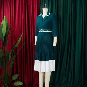 Detail of dark green pleated dress showing contrasting white lapels and pleated hem