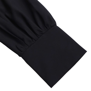 Close-up detail of pleated cuffs on a black elegant dress with woven texture