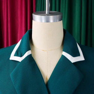Detailed view of dark green blazer lapel featuring elegant white contrast piping detail