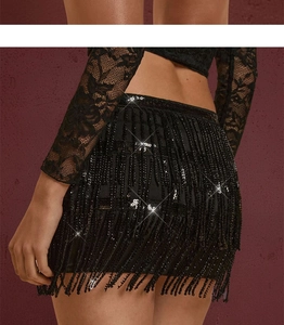Close-up of black sequined mini skirt with long tassels and intricate floral lace top