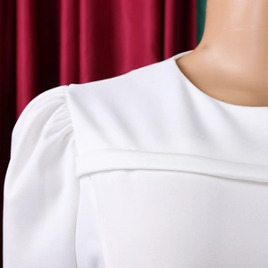 Dettaglio delle eleganti maniche a sbuffo bianche e scollo arricciato su abito da festa