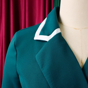 Detail of dark green blazer with white contrast piping on collar and shoulder area