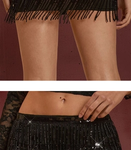 Close-up of black sequined high waist trim and long fringed tassels on a party mini skirt