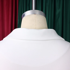 Détail de la robe blanche élégante montrant le revers classique et le tissu texturé