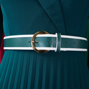 Close-up of pleated dark green dress with gold buckle belt and white stitching detail