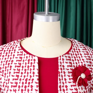 Détail d'une robe rouge avec manteau en tweed à carreaux et broche à fleurs en perles