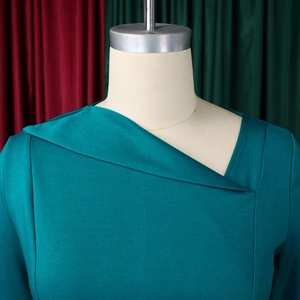 Detailed close-up of asymmetrical folded neckline on a teal dress with fine texture