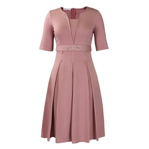 Détail d'une robe plissée rose élégante avec col en V, boucle dorée et boutons décoratifs