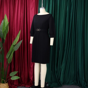 Dettaglio dell'abito midi nero a pieghe con un'elegante cintura con fibbia in vita