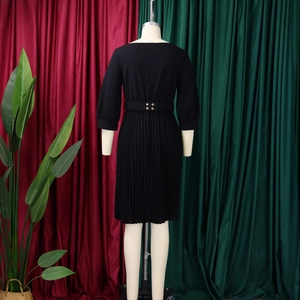 Dettaglio del retro di un abito a pieghe nero con cintura decorata con borchie dorate