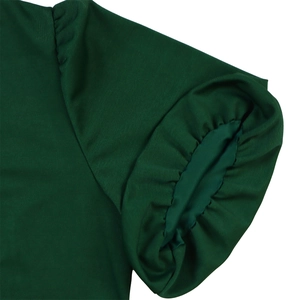 Close-up of deep green dress featuring puff sleeve detail and textured fabric