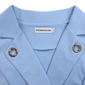 Détail d'un col de blazer bleu clair avec des œillets dorés et une étiquette de marque