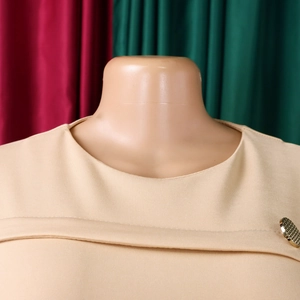 Dettaglio in maglia beige con scollo rotondo e bottone dorato testurizzato elegante