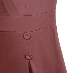 Détail de la taille élégante avec boutons décoratifs sur une robe de couleur rose