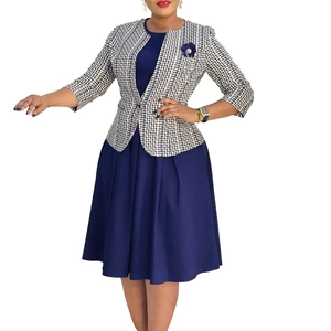 Détail de la robe fourreau bleu marine et du blazer pied-de-poule avec broche fleur