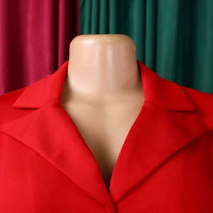 Détail d'une veste de tailleur rouge pour femme avec revers cranté et texture de tissu