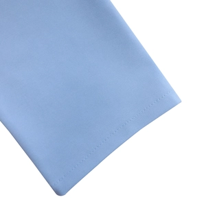 Détail d'une manche de robe bleu clair avec couture double aiguille et texture de tissu fin
