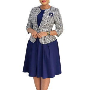 Détail de la robe fourreau bleu marine avec blazer pied-de-poule et broche fleurie