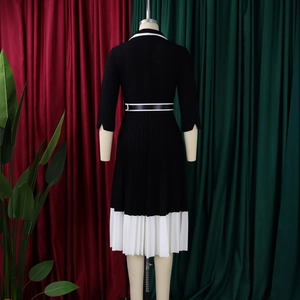 Back view of elegant black knit dress with white contrast collar and pleated hem detail