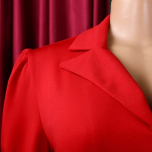 Détail du col à revers rouge et des épaules plissées sur une robe élégante