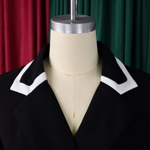 Detail view of contrast white lapel collar on a tailored black long-sleeve dress jacket