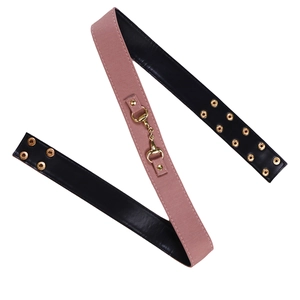 Détail de la ceinture en textile rose et cuir noir avec boucle mors dorée
