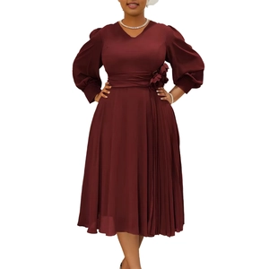 Macro detail of wine red V-neck dress featuring handmade 3D floral accent and pleated skirt