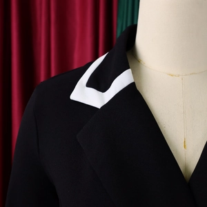 Detail of black blazer shoulder and white contrast lapel edge on a beige mannequin