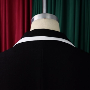 Close-up of neckline detail on black jacket with white contrast piping and sturdy fabric