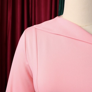 Detailed close-up of the overlapping neckline and shoulder seams of a pink dress