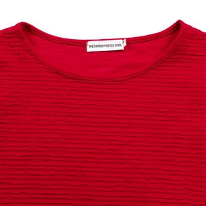 Détail du tissu gaufré rouge et encolure ronde avec étiquette de marque tissée